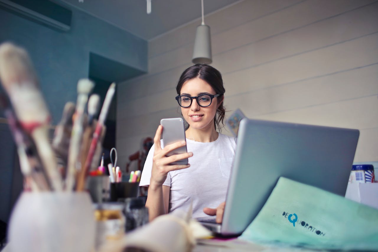 Jeune femme avec un ordinateur portable et un téléphone portable sur son lieu de travail