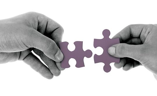 Mans que apropen dues peces de puzzle que encaixen entre elles.