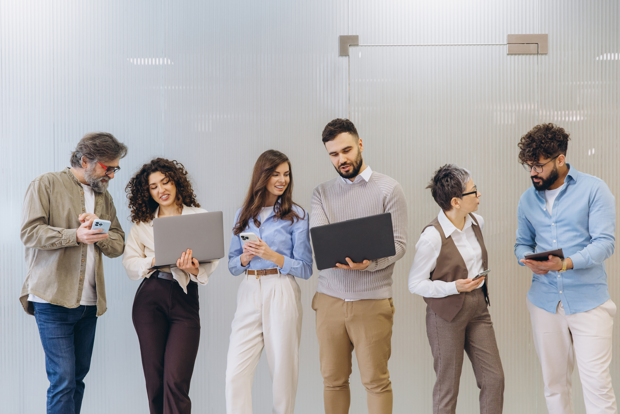 Equip de persones col·laborant en l'oficina utilitzant portàtils i dispositius mòbils